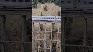 An early era Amtrak Ski Train goes over a wooden trestle bridge