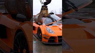 A crane just break a gumpert apollo s in the middle hood and cream just break ceiling with a car