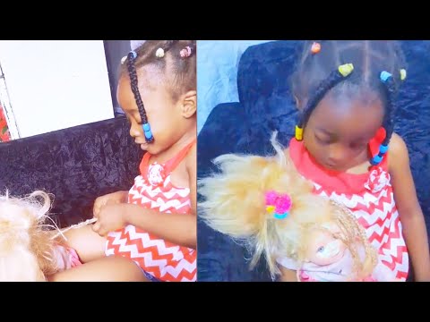 A 4 year old girl makes braids for her doll - Young talent and skills