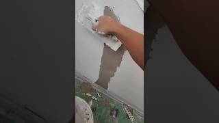 worker using a wide putty knife to repair wall cracks