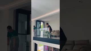 the process of installing large clear glass on the edge of the top floor of a multi-storey building