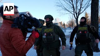 Federal officers push AP reporters back to their car as they document operation